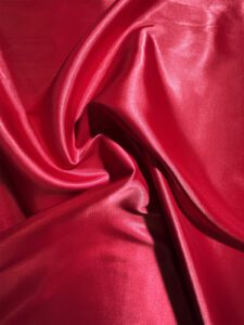 Shiny red silk fabric with smooth folds.